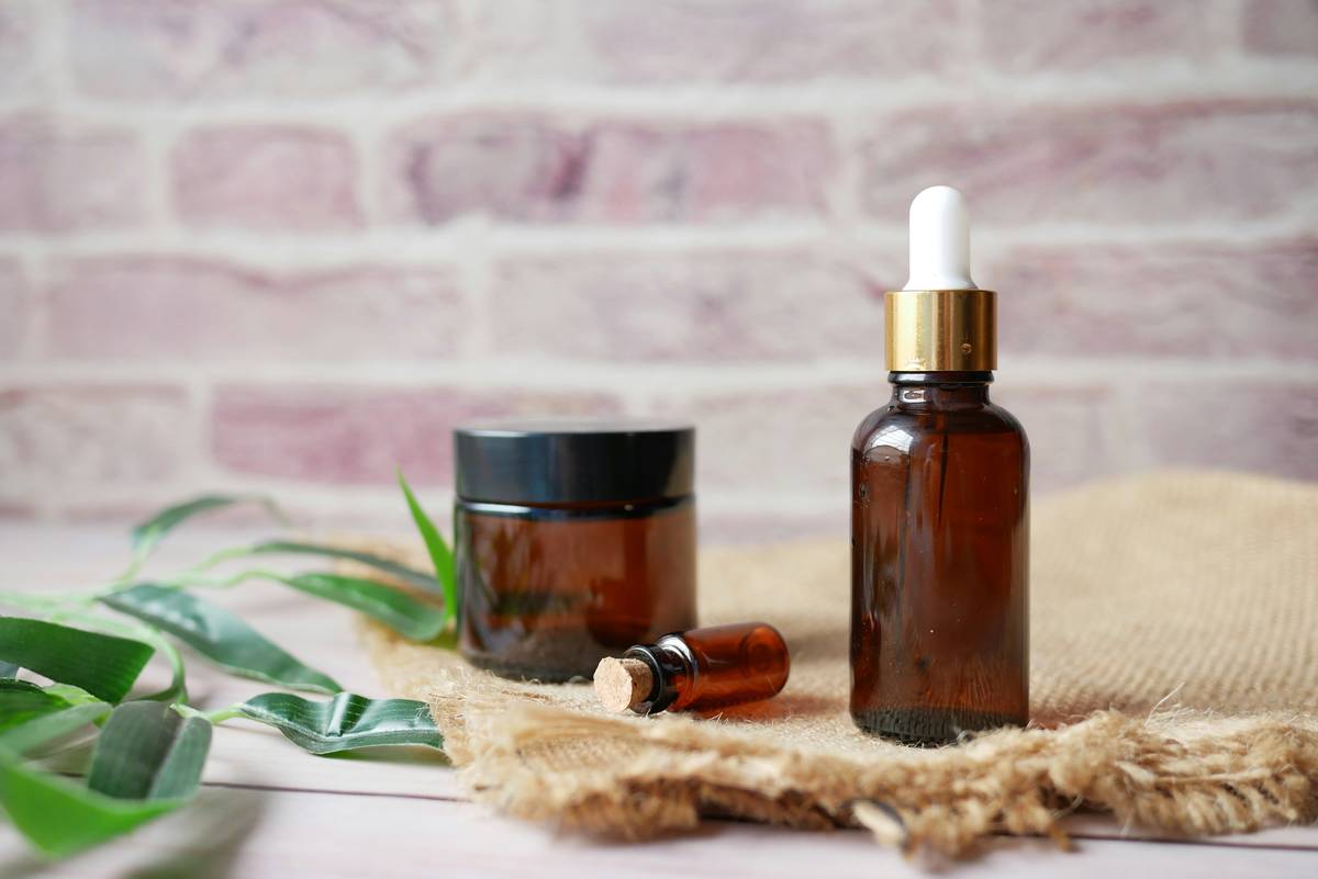 Step-by-step visual guide on how to make aromatherapy bath oil with measuring spoons and amber bottles